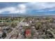 Aerial view of neighborhood with mature trees and a marker indicating property location, cloudy skies and mountain views at 3230 Vance St, Wheat Ridge, CO 80033