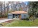 Inviting single-story blue house with a well-kept lawn, mature trees, gray garage, and a serene outdoor setting at 3230 Vance St, Wheat Ridge, CO 80033