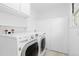 Bright laundry room features modern, white washer and dryer units with shelving and storage at 3230 Vance St, Wheat Ridge, CO 80033