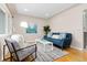 Sunlit living room showcasing hardwood floors, a plush blue sofa, and a chic accent chair with modern decor at 3230 Vance St, Wheat Ridge, CO 80033