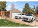 Detached garage with two parked cars on the driveway, a basketball hoop, and surrounding greenery at 2900 Clermont St, Denver, CO 80207