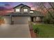 Charming two-story home featuring a two-car garage, well-manicured lawn, and colorful dusk sky at 17522 E Dewberry Dr, Parker, CO 80134