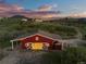 Aerial view of a well-maintained red barn surrounded by lush greenery, showcasing its idyllic location at 3485 Park Ridge Rd, Sedalia, CO 80135