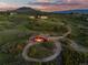 Aerial view of a charming red barn with a circular driveway nestled within a lush, green landscape at 3485 Park Ridge Rd, Sedalia, CO 80135