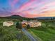 Stunning aerial view of home featuring a landscaped yard, long driveway, guest house, and beautiful sunset backdrop at 3485 Park Ridge Rd, Sedalia, CO 80135