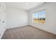 Bright bedroom featuring neutral carpet, white walls, and a large window offering natural light at 1860 Chaffee Crest Dr, Berthoud, CO 80513