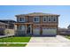 Two-story home with brick and siding, a well-manicured lawn, and an attached three-car garage at 1860 Chaffee Crest Dr, Berthoud, CO 80513