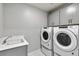 Well-equipped laundry room with modern washer, dryer, sink, and overhead cabinets at 1860 Chaffee Crest Dr, Berthoud, CO 80513