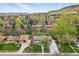 Aerial view of the property showcasing a well-manicured lawn, mature trees, and a paved driveway at 2435 Creighton Dr, Golden, CO 80401