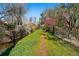 Landscaped backyard with mature trees, green grass, and a stream at 2435 Creighton Dr, Golden, CO 80401