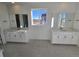 Bathroom with double sinks, white cabinets, large mirrors, and natural light at 5685 Farrier Pt, Castle Rock, CO 80104