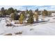 Large backyard with mature trees and wooden fence in a snow covered community at 7863 Windfont Row, Parker, CO 80134