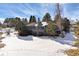 The gray two-story home with a backyard covered in snow and surrounded by mature trees at 7863 Windfont Row, Parker, CO 80134