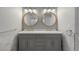 A well lit bathroom featuring a double vanity with round mirrors, modern fixtures, and ample counter space at 7863 Windfont Row, Parker, CO 80134
