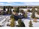 Two-story home with balcony, dark exterior paint, surrounded by mature trees and snow covered grounds with mountain views at 7863 Windfont Row, Parker, CO 80134