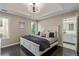 Cozy bedroom features a tray ceiling, dark floors and ensuite bathroom at 618 Fairchild Dr, Highlands Ranch, CO 80126
