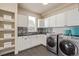 Laundry room with modern appliances, stylish black-and-white tile, and ample storage at 618 Fairchild Dr, Highlands Ranch, CO 80126