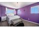 Charming bedroom with a white bed frame, soft purple walls, and two bright windows for ample natural light at 5475 Shoshone Dr, Longmont, CO 80504