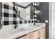 Modern bathroom with black and white buffalo check wallpaper, round mirror and double vanity at 7033 E Lake Cir, Centennial, CO 80111