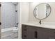 Modern bathroom with stylish round mirror, gray vanity, and hexagon shower tiles at 7778 Windwood Way, Parker, CO 80134