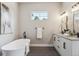 This modern bathroom features a freestanding tub, gray tile floor, and double vanity with white cabinets at 7778 Windwood Way, Parker, CO 80134