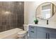 This bathroom features a tub and shower, black tile, and a vanity with a round mirror at 7778 Windwood Way, Parker, CO 80134