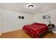 Bedroom with hardwood floors, two windows, and a red-and-black plaid bedspread at 109 S Fulton Ave, Fort Lupton, CO 80621