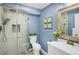 Stylish blue bathroom featuring a glass shower, toilet, and sink with decorative mirror at 3529 S Telluride Cir # D, Aurora, CO 80013