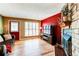 Living room featuring a stone fireplace, wood-look flooring, bright windows, and a red accent wall at 9565 W Coal Mine Ave # A, Littleton, CO 80123