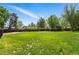 Expansive backyard with lush green grass, mature trees, and a wood perimeter fence at 1354 S Macon St, Aurora, CO 80012