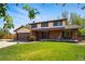 Two-story home features brick accents, a well-kept lawn, and mature trees enhancing its inviting charm at 1354 S Macon St, Aurora, CO 80012