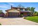 Inviting home exterior showcasing the garage, brick accents, and lush lawn enhancing curb appeal at 1354 S Macon St, Aurora, CO 80012
