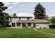 Large backyard features a well-manicured lawn, patio seating area, and mature trees providing shade and privacy at 3930 S Hillcrest Dr, Denver, CO 80237
