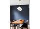 Modern dining room with wood table, chairs and designer lighting fixture with navy blue accent wall at 3930 S Hillcrest Dr, Denver, CO 80237