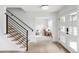 Bright and modern foyer with light wood floors, a staircase with black railings, and a view into the living room at 3930 S Hillcrest Dr, Denver, CO 80237