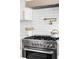 Close up of modern stove with sleek white tile backsplash and stainless steel appliances at 3930 S Hillcrest Dr, Denver, CO 80237