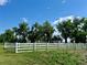 Lawn view with a white fence and mature trees under a bright blue sky at 22400 County Road 10, Hudson, CO 80642
