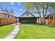 Charming home's backyard showcasing a well-kept lawn, stone pathway, covered porch, mature trees, and inviting curb appeal at 3680 S Logan St, Englewood, CO 80113