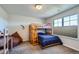 Cozy bedroom features a classic wooden bunkbed with blue bedding, soft carpet, and a large window for ample natural light at 2272 Front Range Rd, Erie, CO 80516