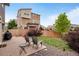 Cozy backyard patio with chairs, barbecue, small table, and landscaped yard enclosed by a wooden fence at 18173 E 104Th Way, Commerce City, CO 80022