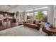 Sunlit living room featuring large windows, plush seating, and an open layout with a kitchen view at 18173 E 104Th Way, Commerce City, CO 80022