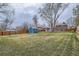 Large backyard with green lawn, storage shed, and a partial view of the brick home, perfect for outdoor activities at 6970 Upham St, Arvada, CO 80003