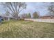 Spacious backyard with lush lawn and mature trees surrounding the brick home, creating a private oasis at 6970 Upham St, Arvada, CO 80003