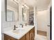 Renovated bathroom featuring double sinks, quartz counters, and open towel storage at 6970 Upham St, Arvada, CO 80003