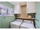 Functional laundry room with modern washer and dryer, ample storage cabinets, and a bright window at 6970 Upham St, Arvada, CO 80003