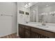 Bathroom featuring double sink, white countertop, dark cabinets, large mirror, and glass-door shower at 16099 Alberta Dr, Parker, CO 80134