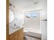 Bright bathroom with a white tiled shower and tub combo, a modern vanity, and a window with a view at 4258 Tennyson St # 101, Denver, CO 80212