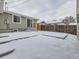 A quaint backyard with a wooden fence and small deck is covered in snow during the winter months at 4844 Vallejo St, Denver, CO 80221