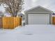 Detached garage with white door and wooden fence in backyard covered in a blanket of winter snow at 4844 Vallejo St, Denver, CO 80221