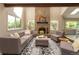 Bright living room featuring a brick fireplace, high ceilings, and large windows offering views of the outdoor scenery at 8160 W Phillips W Ave, Littleton, CO 80128